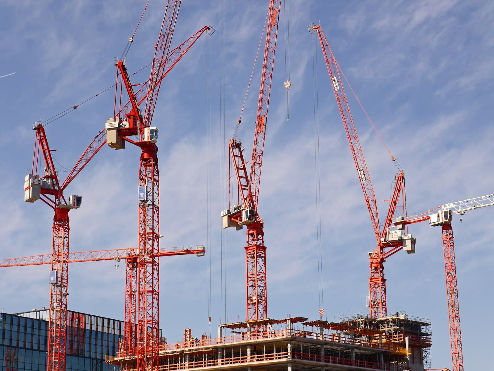 Tower cranes above a construction site under a blue sky